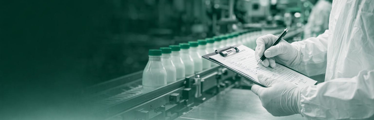Person in a sterile environment with a tablet and bottles on a conveyor belt